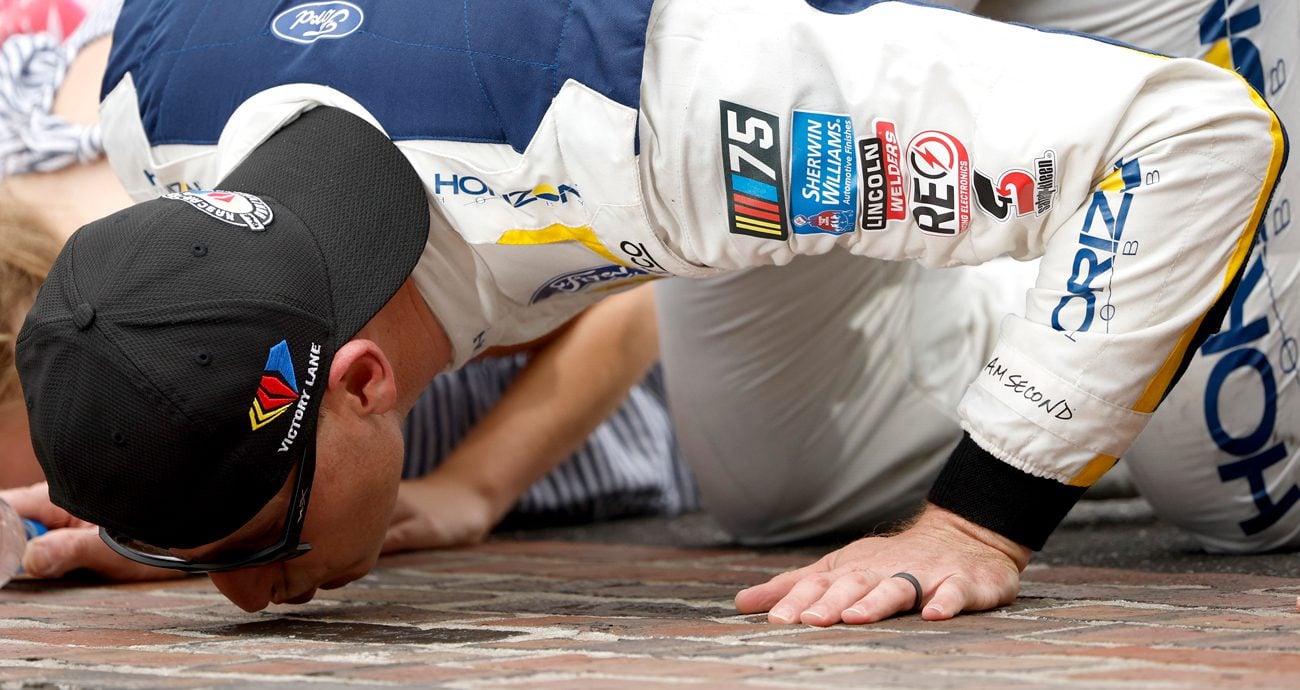 Michael McDowell kisses the bricks following his NASCAR Cup Series win at the Indianapolis Motor Speedway Road Course.