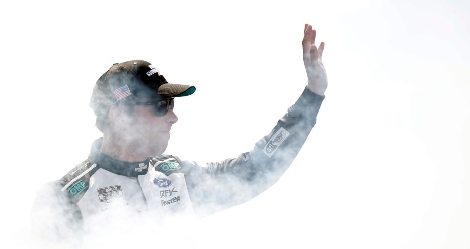 Brad Keselowski emerges through white smoke smiling and waving to fans during driver introductions