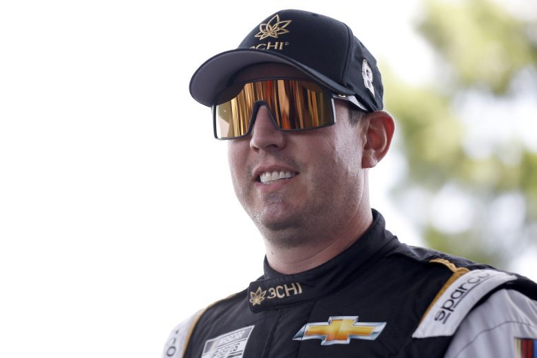 Kyle Busch smiles while wearing a hat and sunglasses