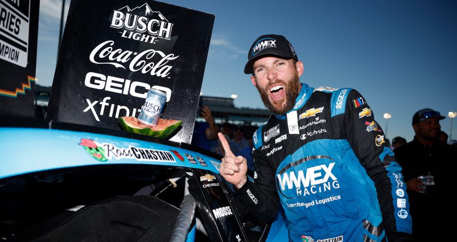 Ross Chastain celebrates his Phoenix win in Victory Lane, holding up his right index finger while a can of Busch Light beer sits within a half-eaten watermelon