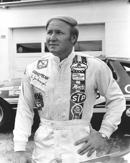 Cale Yarborough poses in front of race car.