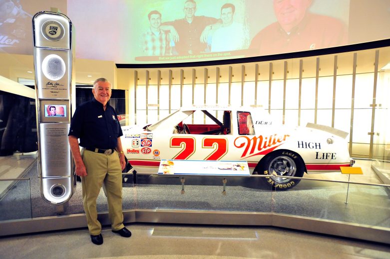 Rusty Wallace poses next to No. 22 race car at the NASCAR Hall of Fame.