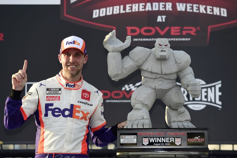 Denny Hamlin poses next to race winning trophy