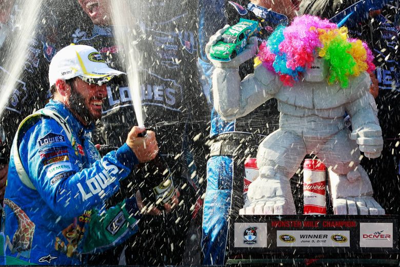 Jimmie Johnson sprays champagne next to race winning trophy