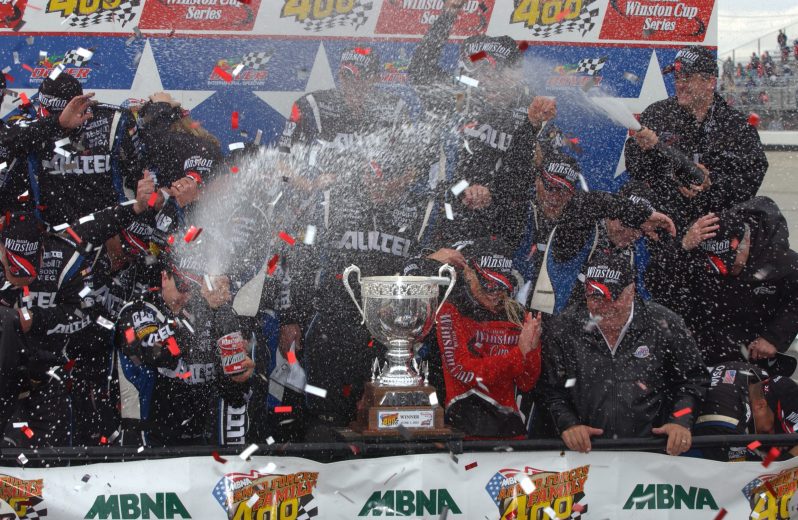 Ryan Newman and crew hold up racing winning banner in Victory Lane.