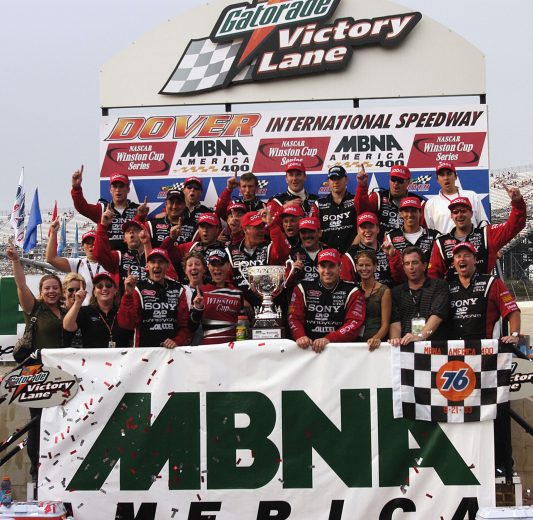 Ryan Newman and crew hold up racing winning banner in Victory Lane.