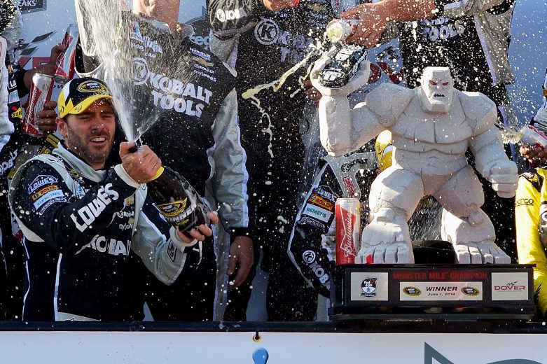 Jimmie Johnson sprays champagne next to trophy