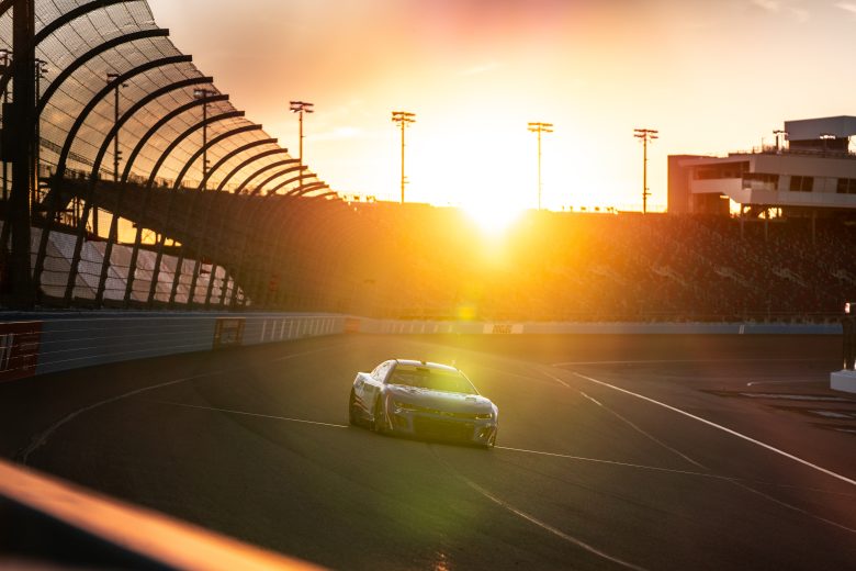 Kyle Larson drives the No. 5 Chevrolet into Turn 1 at Phoenix Raceway with the sun setting in the background during a NASCAR Cup Series test.