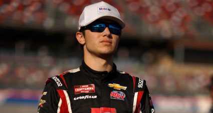 Chase Purdy stands on pit road wearing a white hat and black sunglasses.