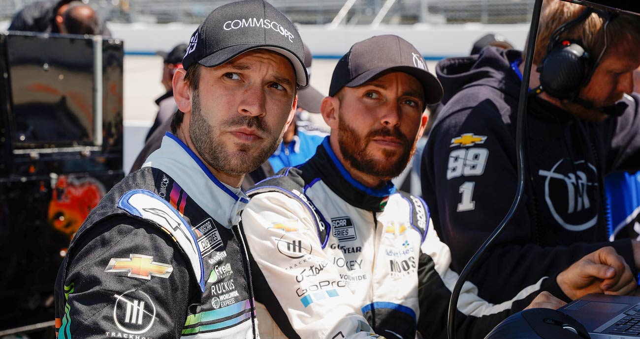 Daniel Suárez, foreground, and Ross Chastain, background, look on before a NASCAR Cup Series race.