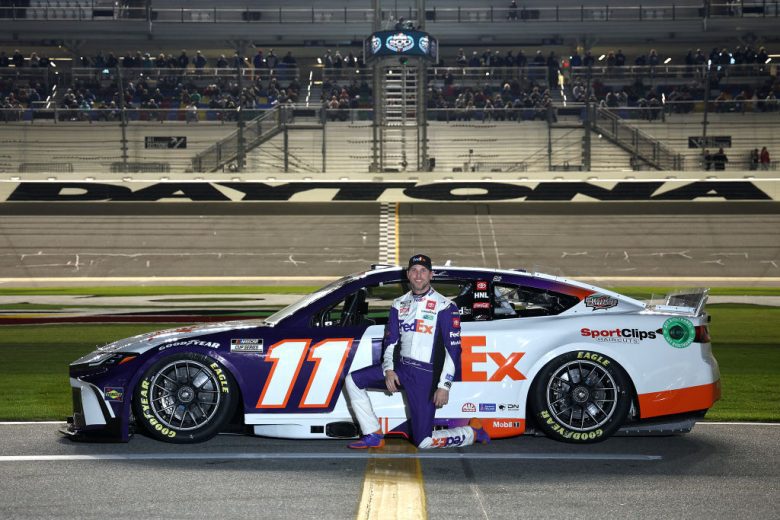 Denny Hamlin poses for a photo next to his No. 11 Toyota at Daytona International Speedway.