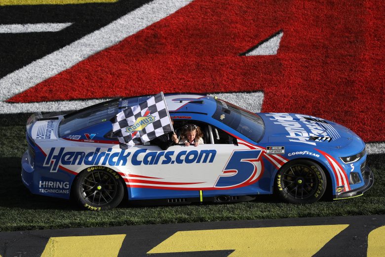 Kyle Larson ad his kids who are holding the checkered flag out of the passenger window drive to Victory Lane in his number 5 Chevrolet.