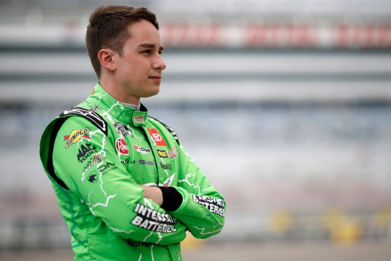 Christopher Bell crosses his arms and looks on.