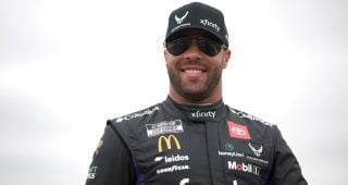 Bubba Wallace smiles on pit road ahead of a NASCAR Cup Series race.