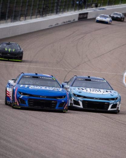Kyle Larson (L) and Ross Chastain (R) race side-by-side at Kansas Speedway.