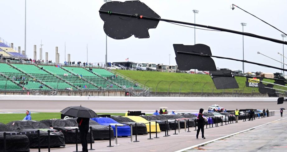A general view of pit road with cars covered up due to weather at Kansas Speedway.