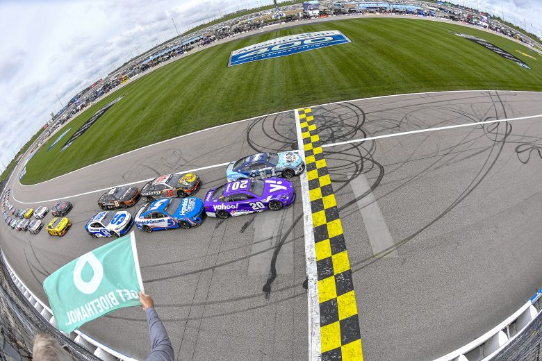NASCAR Cup Series cars cross the start/finish line at the wave of the green flag at Kansas Speedway.