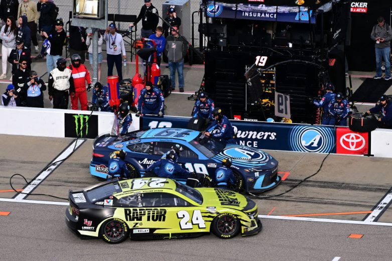 The No. 24 Hendrick Motorsports Chevrolet of William Byron passes by the No. 19 Joe Gibbs Racing Toyota of Martin Truex Jr. on pit road at Kansas Speedway.