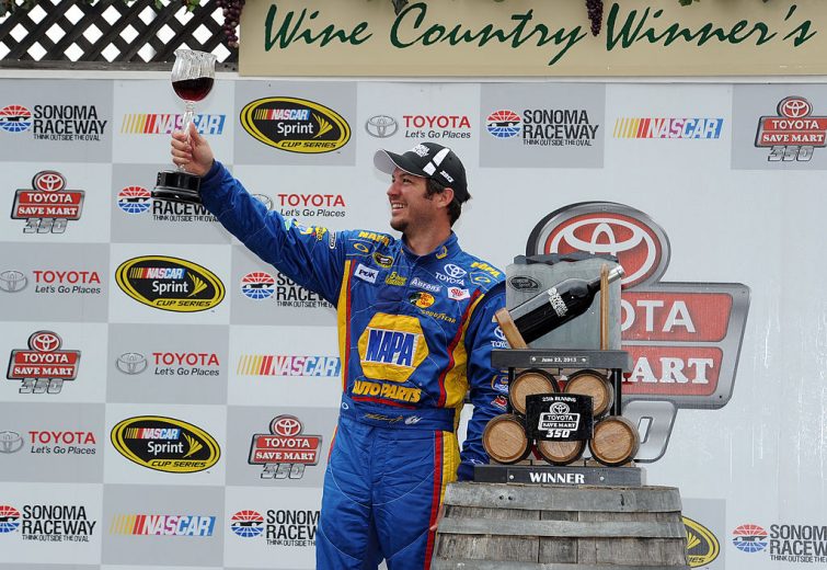 Martin Truex Jr. raises a wine glass in Victory Lane following his NASCAR Cup Series victory at Sonoma Raceway.