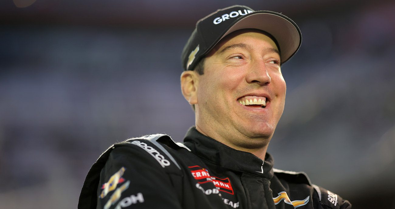 Kyle Busch smiles and laughs on pit road ahead of a NASCAR race.