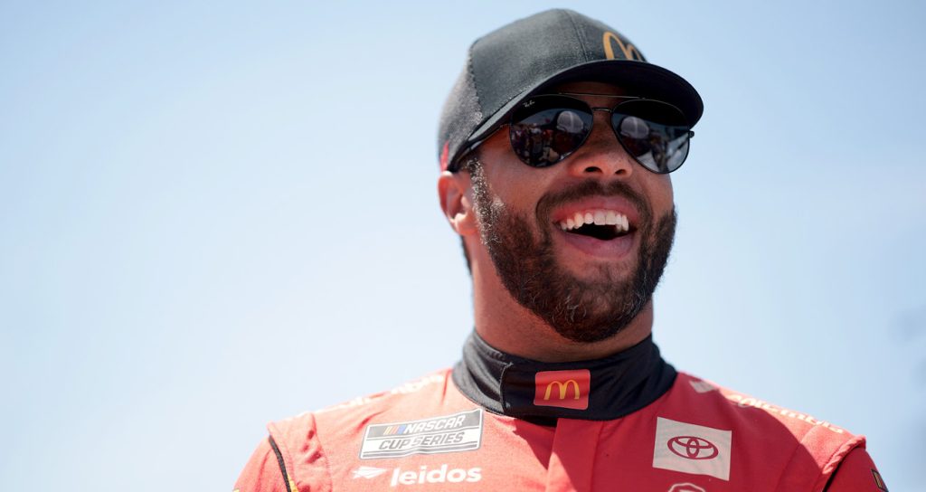 23XI Racing driver Bubba Wallace smiles on pit road ahead of a NASCAR Cup Series race.