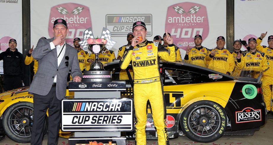 Christopher Bell, driver of the No. 20 DEWALT Toyota, and Atlanta Motor Speedway General Manager, Brandon Hutchison celebrate in victory lane after winning the NASCAR Cup Series Ambetter Health 400