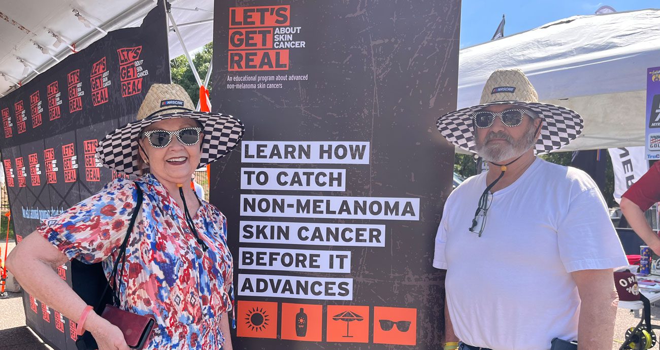 A couple stands in front of a sign.
