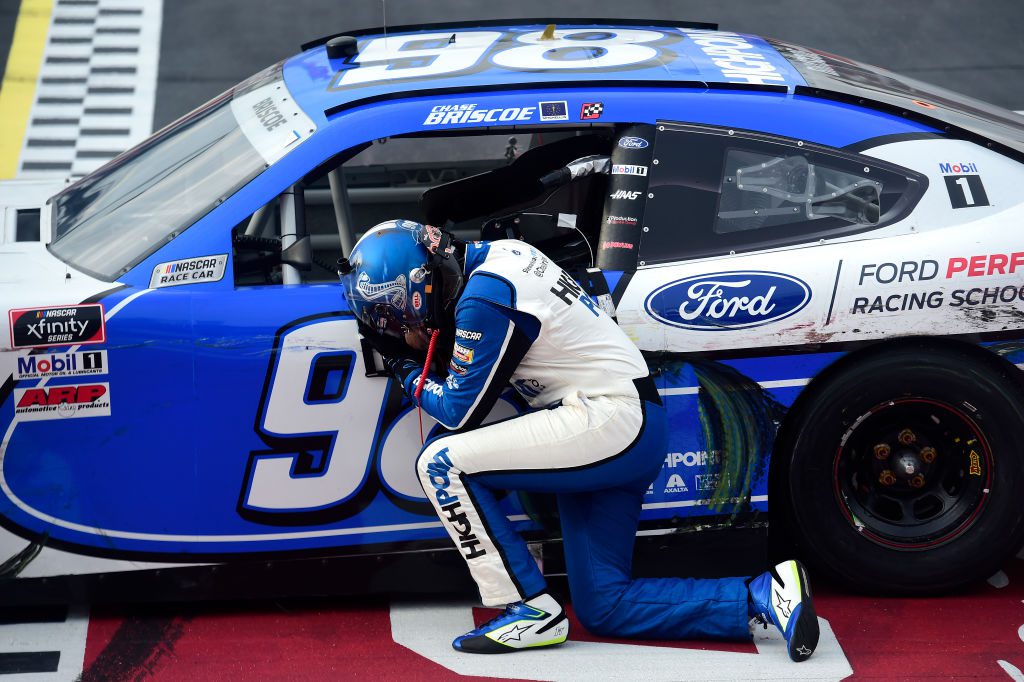 Chase Briscoe kneels next to his race car after an Xfinity Series win at Darlington.