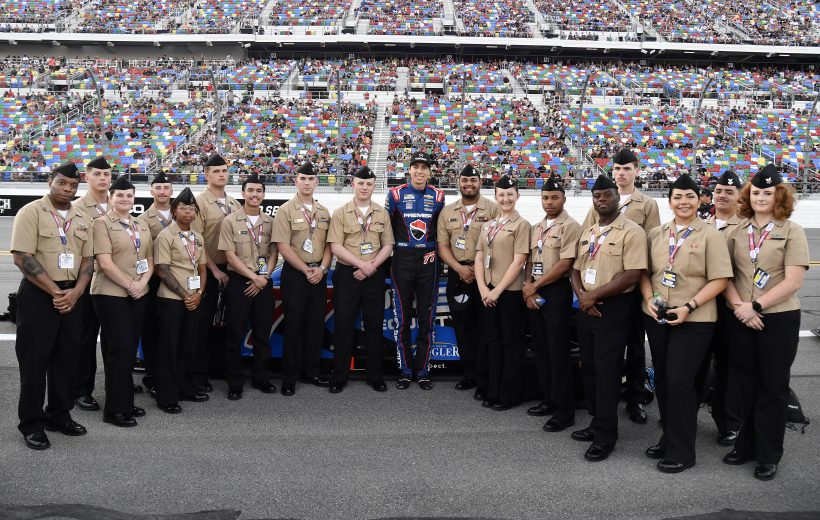 Carson Hocevar poses with U.S. military service members at Daytona International Speedway.