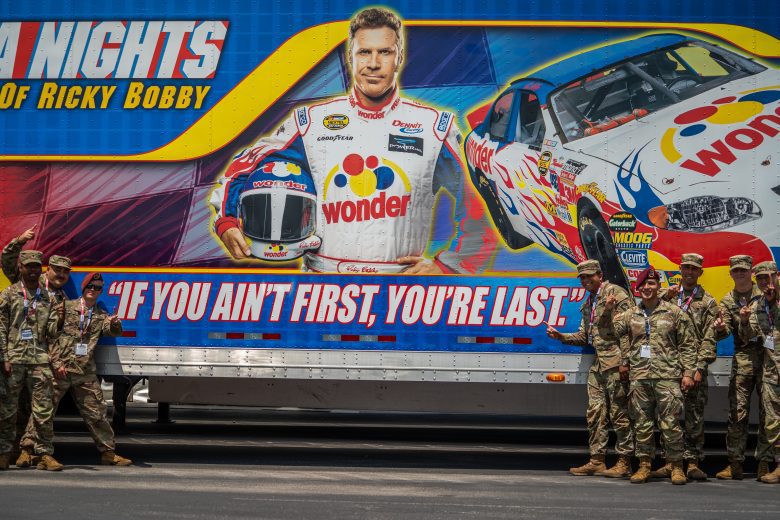 U.S. military service members pose for a photo with a Talladega Nights: The Ballad of Ricky Bobby trailer.