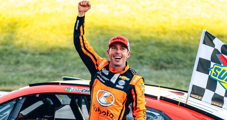 Ross Chastain raises his fist toward the crowd in celebration following his NASCAR Cup Series win at Kansas Speedway.