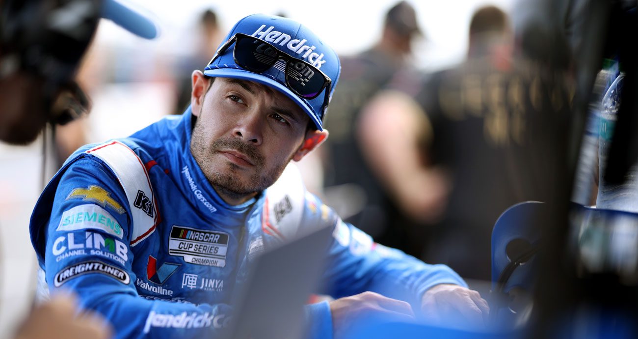 Kyle Larson talks with crew members in the pit area at Daytona.