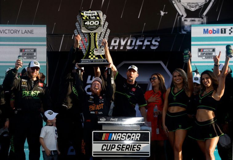 Tyler Reddick raises the victory trophy at Homestead-Miami Speedway while his team surrounds him in Victory Lane.