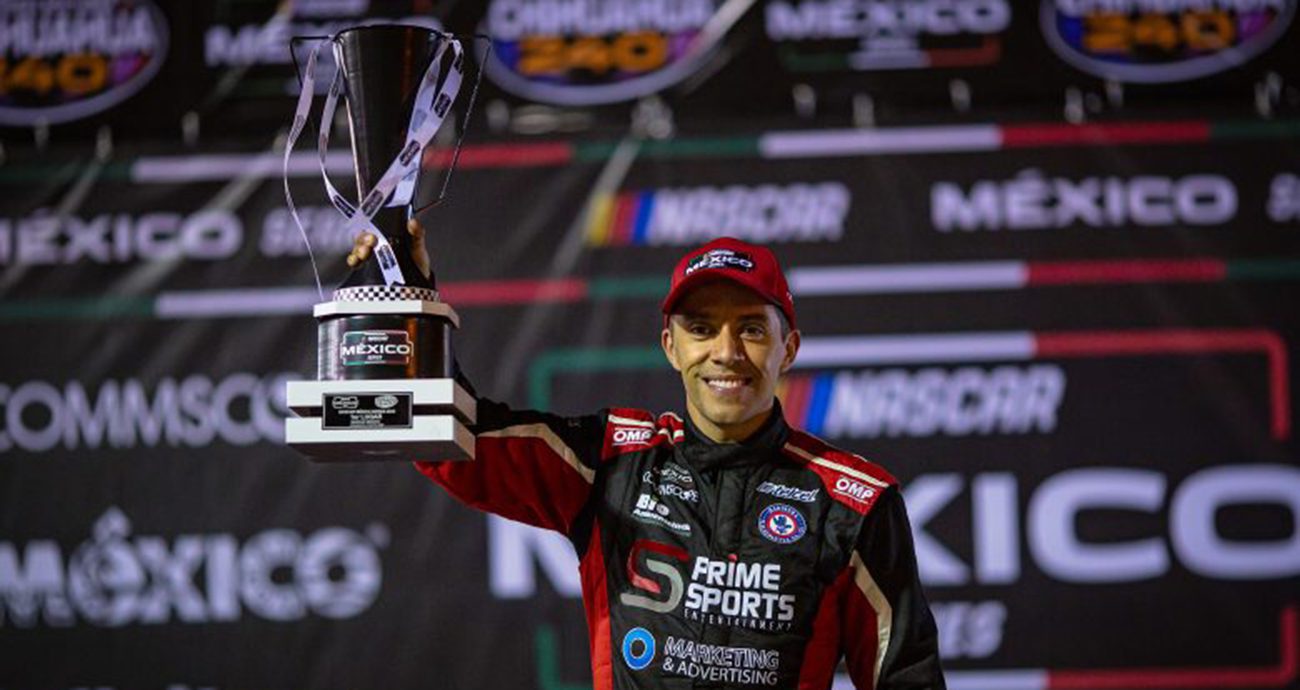 Xavi Razo lifts trophy in Victory Lane.