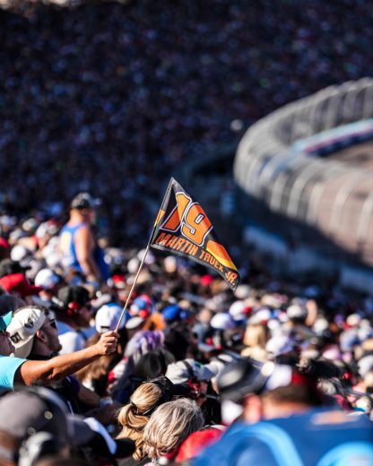 A fan waves a No. 19 flag in the grandstands at Phoenix Raceway.