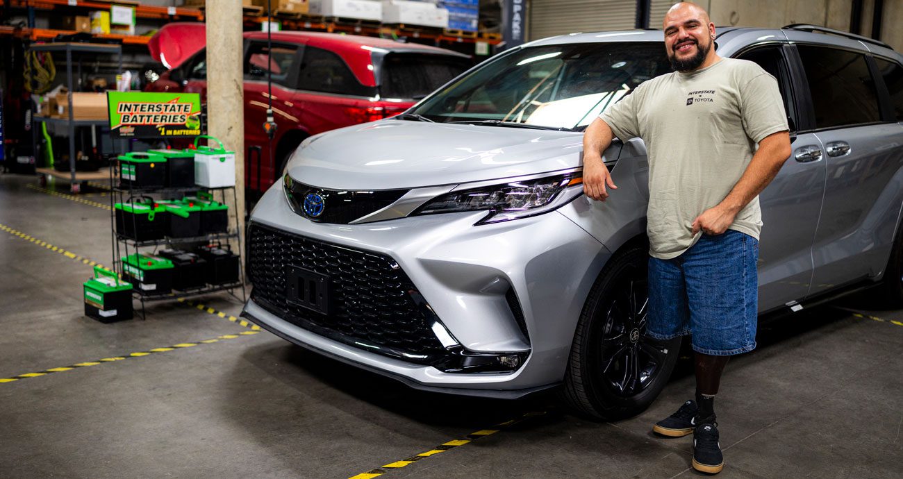 Julian Torres poses for a photo, leaning on a car