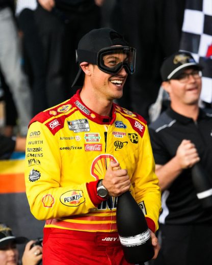 Joey Logano holds a bottle of victory champagne.