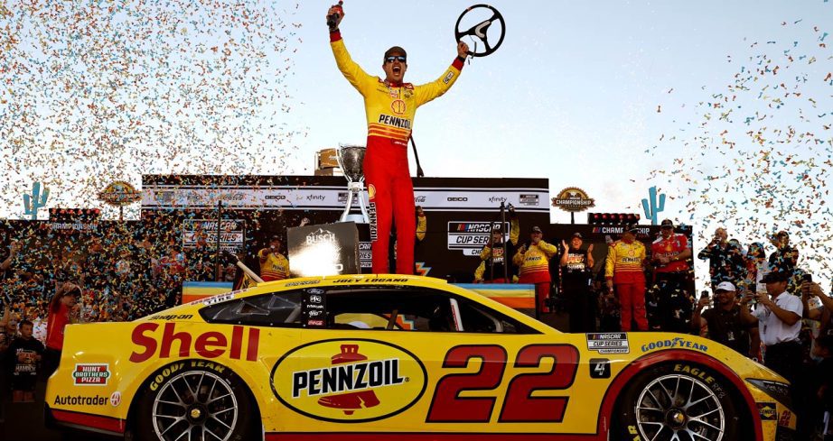Joey Logano stands atop his No. 22 Team Penske Ford in Victory Lane and celebrates.