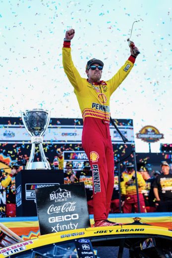 Joey Logano raises his hands in celebration in Victory Lane.