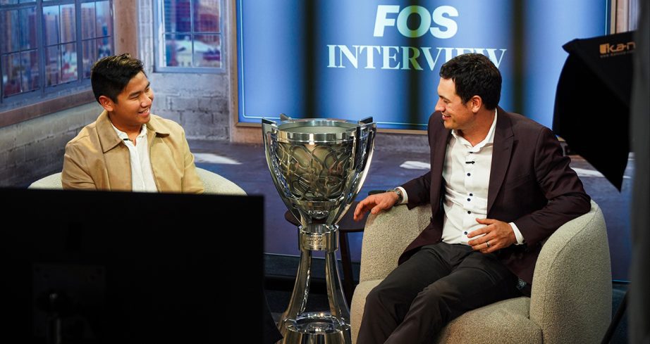Joey Logano sits in an interview and smiles while next to the Bill France Cup.