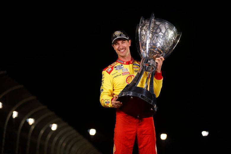 Joey Logano poses with the championship trophy.