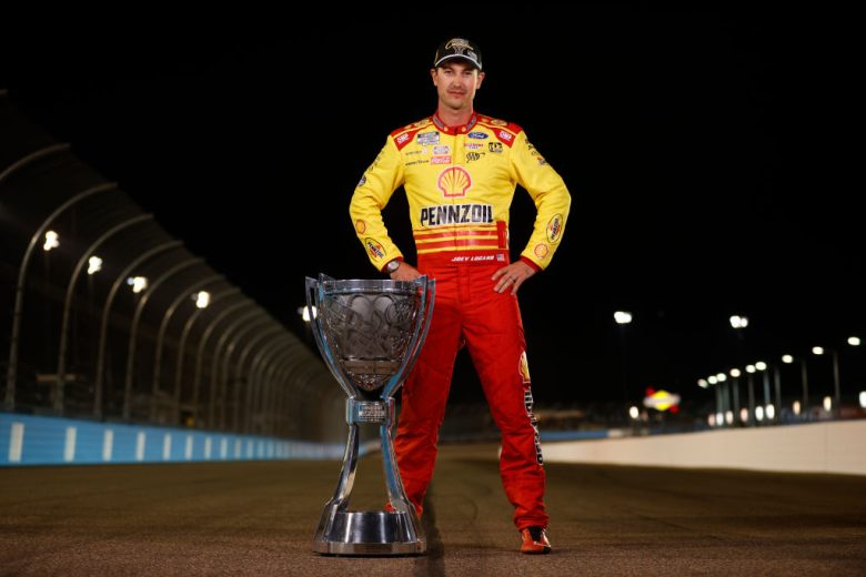 Joey Logano poses with the championship trophy.
