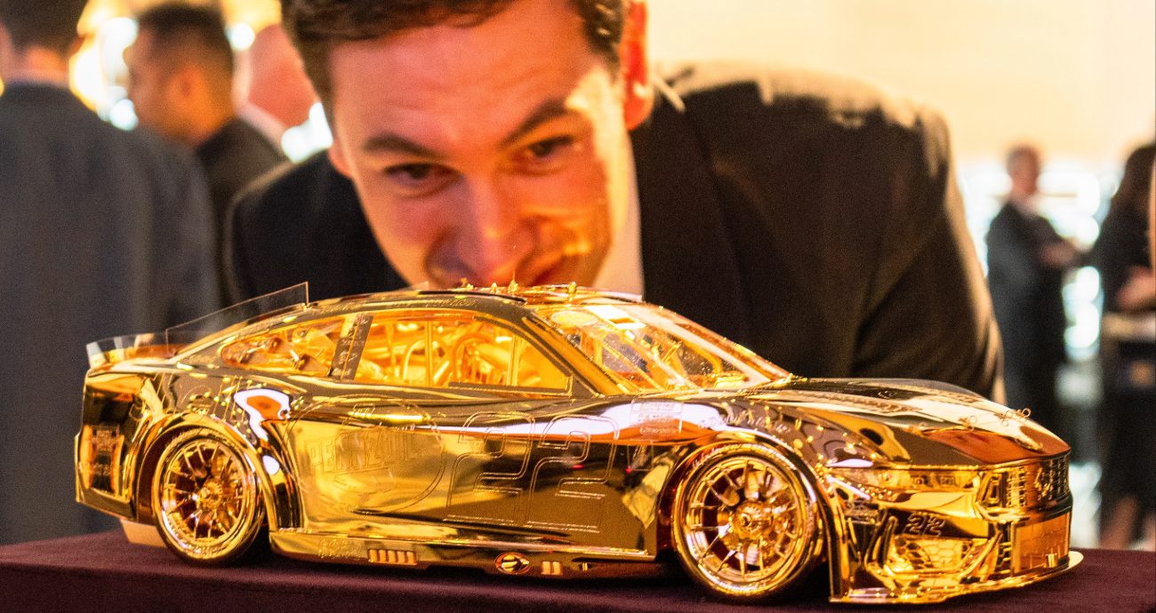 Joey Logano looks at the Goodyear gold car.