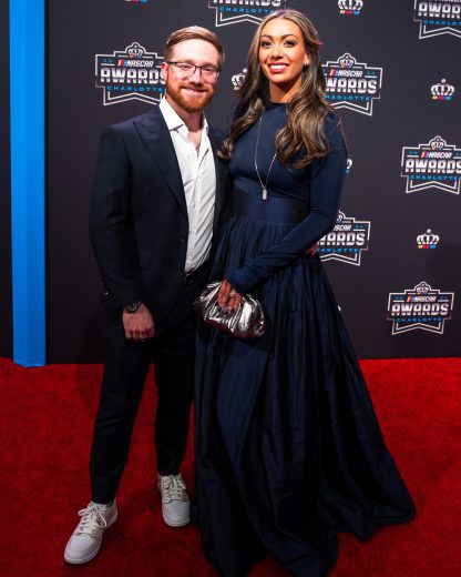 Tyler Reddick poses for photos with his wife on the red carpet.
