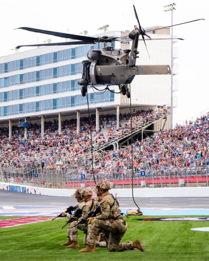 Members of the United States Armed Forces exit a military helicopter during a pre-race ceremony at Charlotte Motor Speedway.