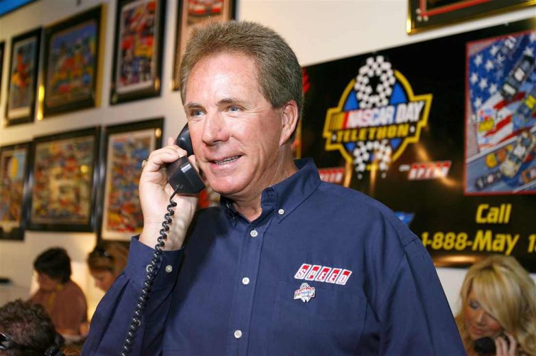 Darrell Waltrip looks on.