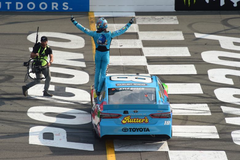 Kyle Busch climbs out of No. 18 Toyota and celebrates at the finish line.