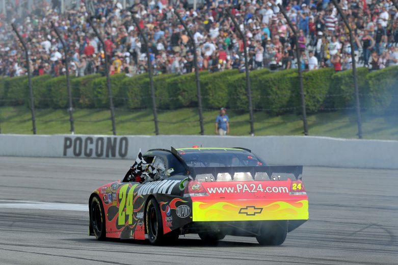 Jeff Gordon celebrates and hold checkered flag with driving.
