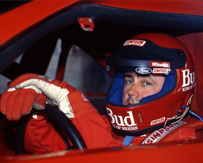 Geoff Bodine sits in seat with helmet on.