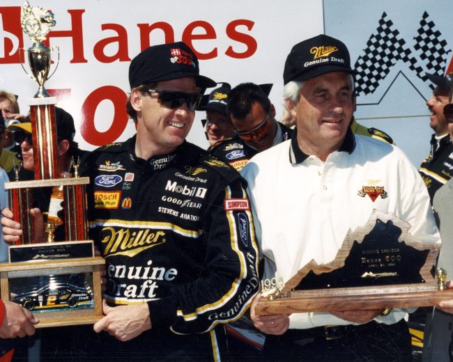 Driver Rusty Wallace and his car owner Roger Penske receive their trophies in victory lane.